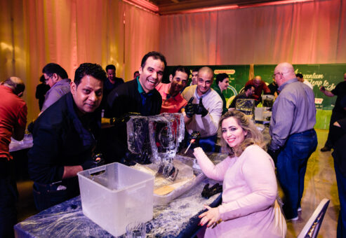 A team enthusiastically works together on their ice sculpting project during a Team building Ice Sculpting event, displaying their creativity and collaboration skills.