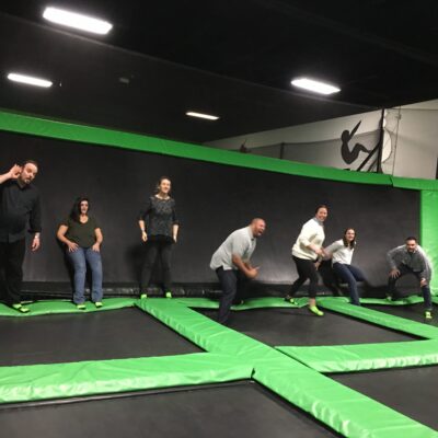 Team members bouncing with joy on trampolines during a Mystery Bus team building event, adding fun and energy to their day of surprises and adventure. thumbnail