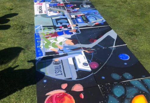 A completed space-themed mural with vibrant images of planets, astronauts, and the word 