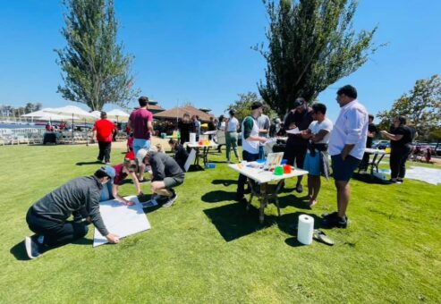 Teams collaborate outdoors on individual canvases during The Big Picture team building event, working together to create a collective mural that promotes communication and teamwork.