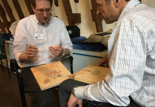 Two participants engage in a reflective moment, writing on wooden boards during a board-breaking team building event aimed at overcoming personal and professional barriers.