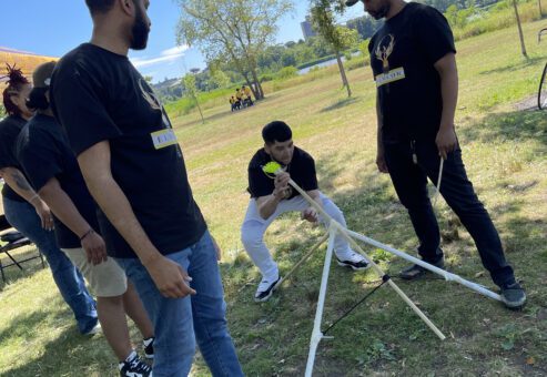Participants outdoors collaborating on building a catapult during the Catapult to Success team building activity, showcasing teamwork, problem-solving, and creativity in a natural setting.