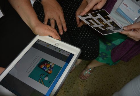 Participants solve clues from an iPad during the Escape the Mob team building event, working together to complete a high-tech scavenger hunt and uncover the missing diamonds.