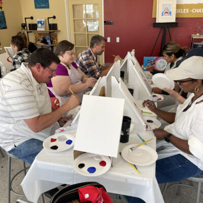 Participants in The Mystery Bus team building event paint canvases, engaging in a creative and collaborative experience. thumbnail