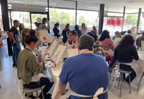 Team members participate in a painting activity during The Mystery Bus team building event, focusing on creativity and collaboration.