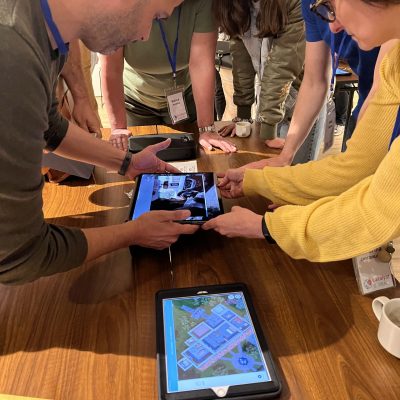 Team members collaborating and using tablets to explore evidence in the interactive 3D crime scene of the Corporate CSI team building event. thumbnail