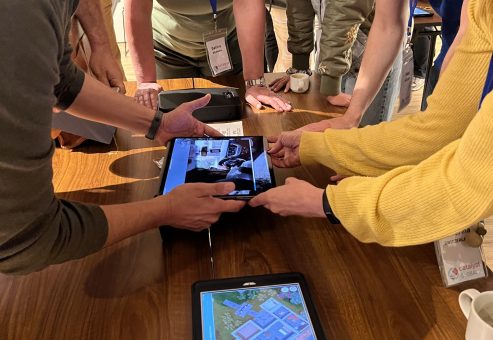 Team members collaborating and using tablets to explore evidence in the interactive 3D crime scene of the Corporate CSI team building event.