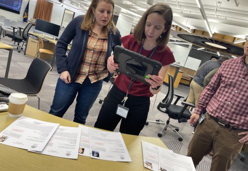 Participants analyze case files and use a tablet to uncover clues during the Corporate CSI team building activity.