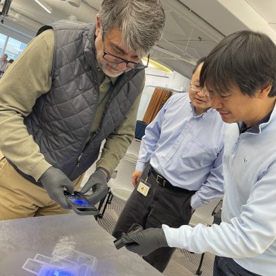 Participants using UV light to inspect a crime scene map during the Corporate CSI team building event.. thumbnail