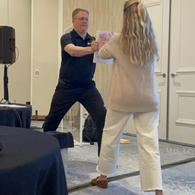 A facilitator guides a participant through a board-breaking exercise during a transformative team building event focused on overcoming barriers. thumbnail