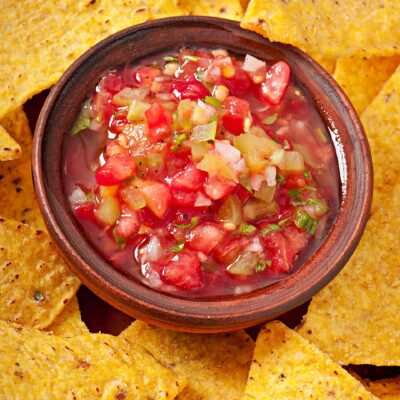 A vibrant bowl of fresh salsa surrounded by crispy tortilla chips, showcasing the flavors created during the Salsa Showdown team building event. thumbnail