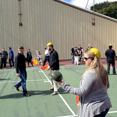 Teams participating in the Catapult to Success team building activity, engaging in hands-on construction of catapults while strategizing and collaborating on a tennis court setting. thumbnail