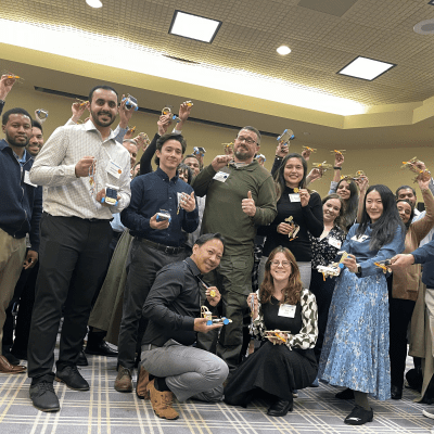 Participants proudly holding their STEM race car creations after a successful team building session at STEM Speedway. thumbnail