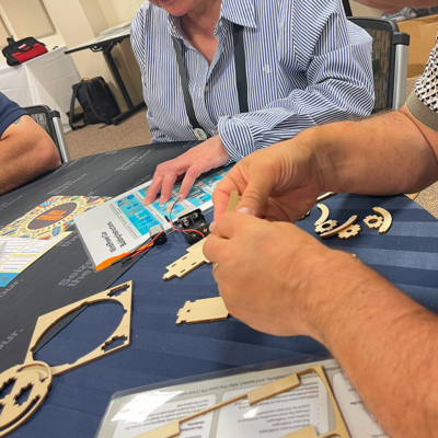 Participants assembling wooden parts of a STEM project kit during the STEM Speedway team building activity, focusing on teamwork, attention to detail, and hands-on construction. thumbnail
